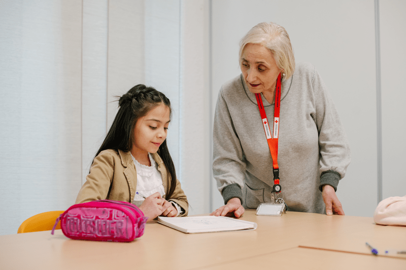 Une bénévole aide une jeune demandeuse d'asile a ses devoirs