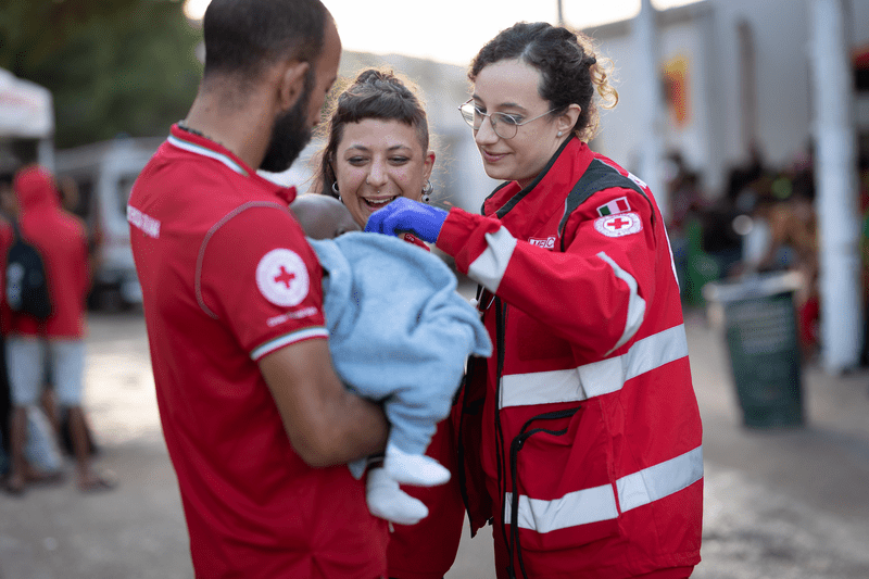 Bébé migrant dans les bras d'un bénévole